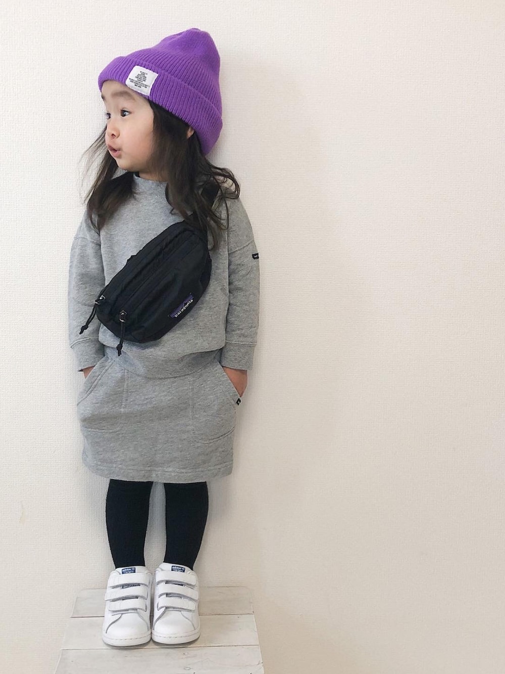 グレー系のスカート、ホワイト系のスニーカー、パープル系のニットキャップ/ビーニーを着用したキッズの春コーディネートの2枚目の写真