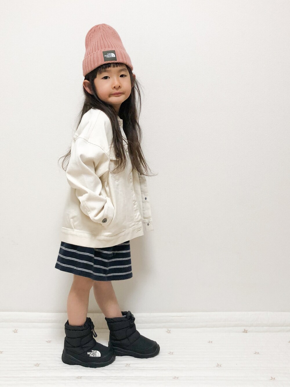 ホワイト系のデニムジャケット、ブラック系のブーツ、ピンク系のキャップを着用したキッズの春コーディネートの3枚目の写真