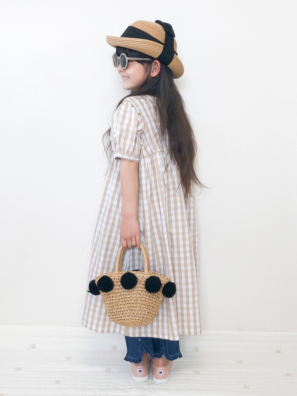 ベージュ系のシャツワンピース、ベージュ系のデニムパンツを着用したキッズの夏コーディネートの2枚目の写真