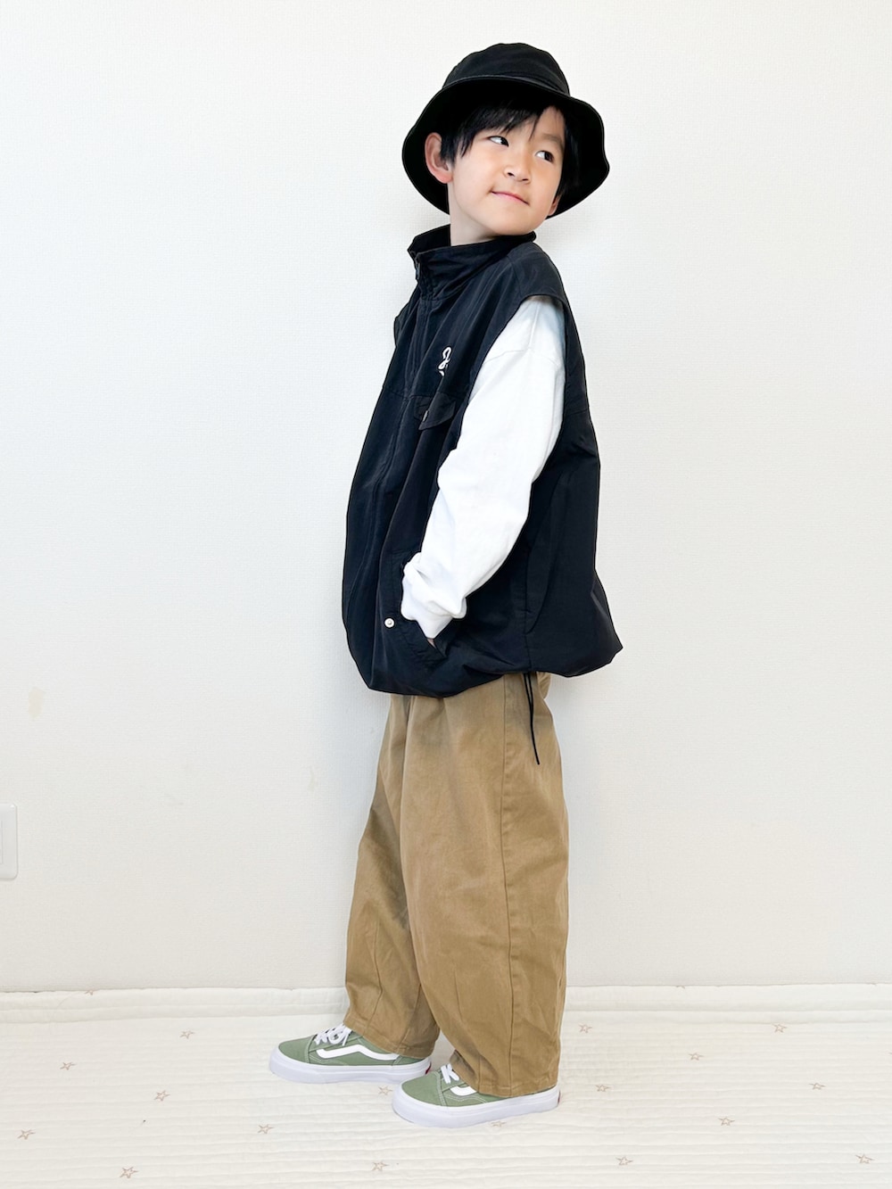 ベージュ系のその他パンツ、グリーン系のスニーカー、ブラック系のベストを着用したキッズの春コーディネートの2枚目の写真