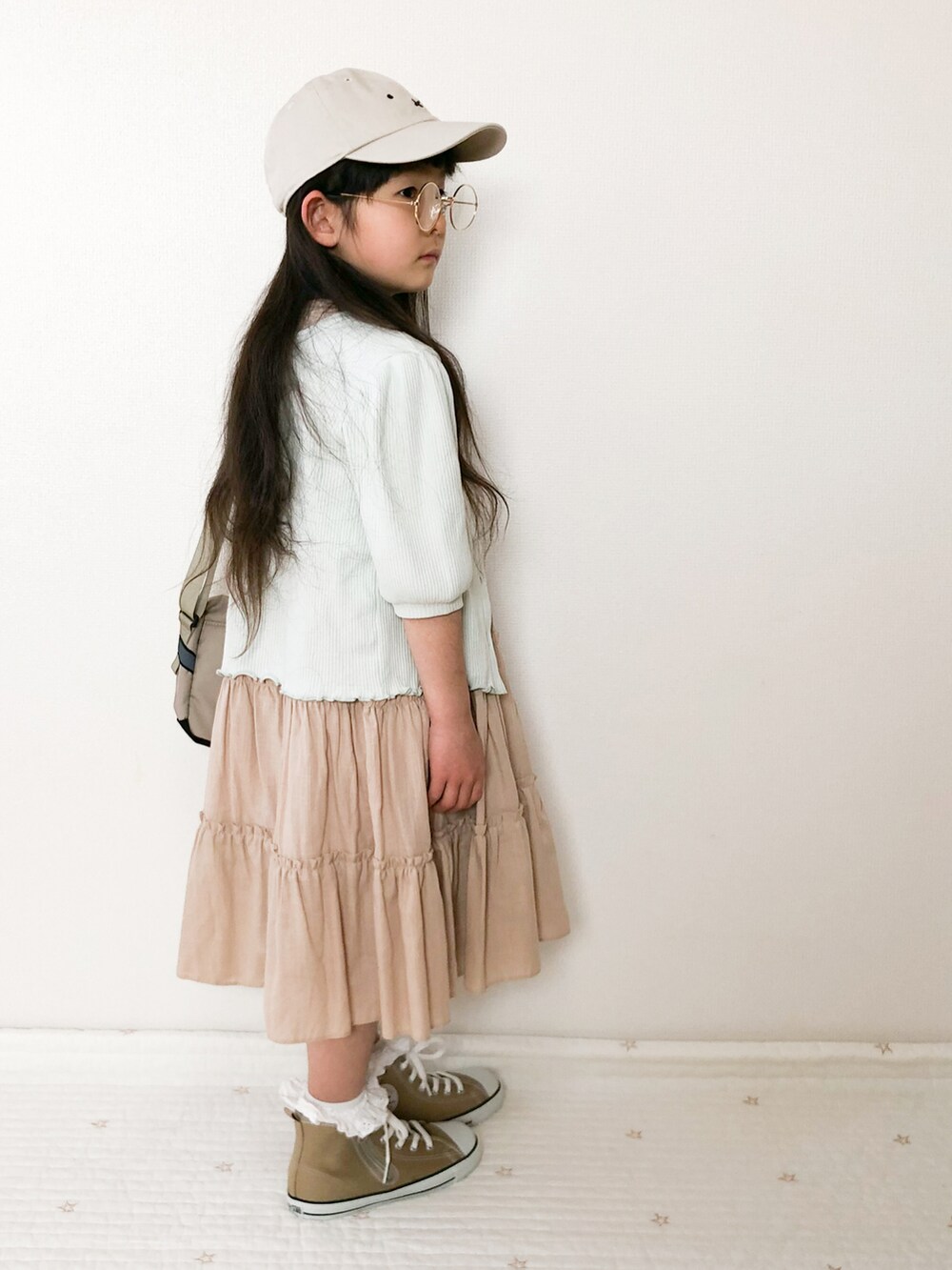 ベージュ系のショルダーバッグ、グリーン系のカーディガン/ボレロ、ベージュ系のスニーカーを着用したキッズの春コーディネートの3枚目の写真