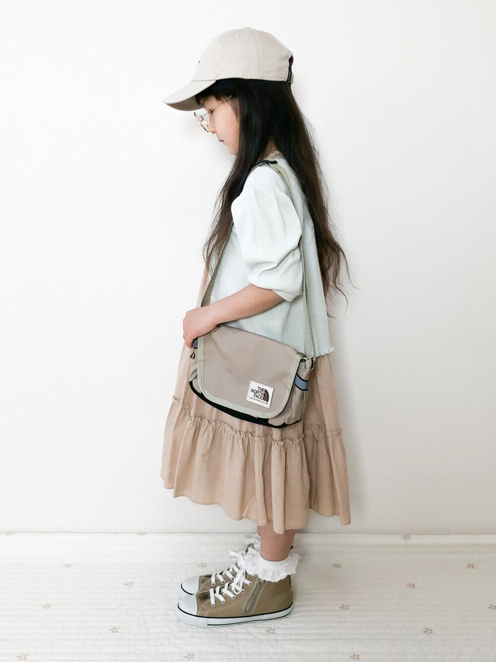 ベージュ系のショルダーバッグ、グリーン系のカーディガン/ボレロ、ベージュ系のスニーカーを着用したキッズの春コーディネートの2枚目の写真