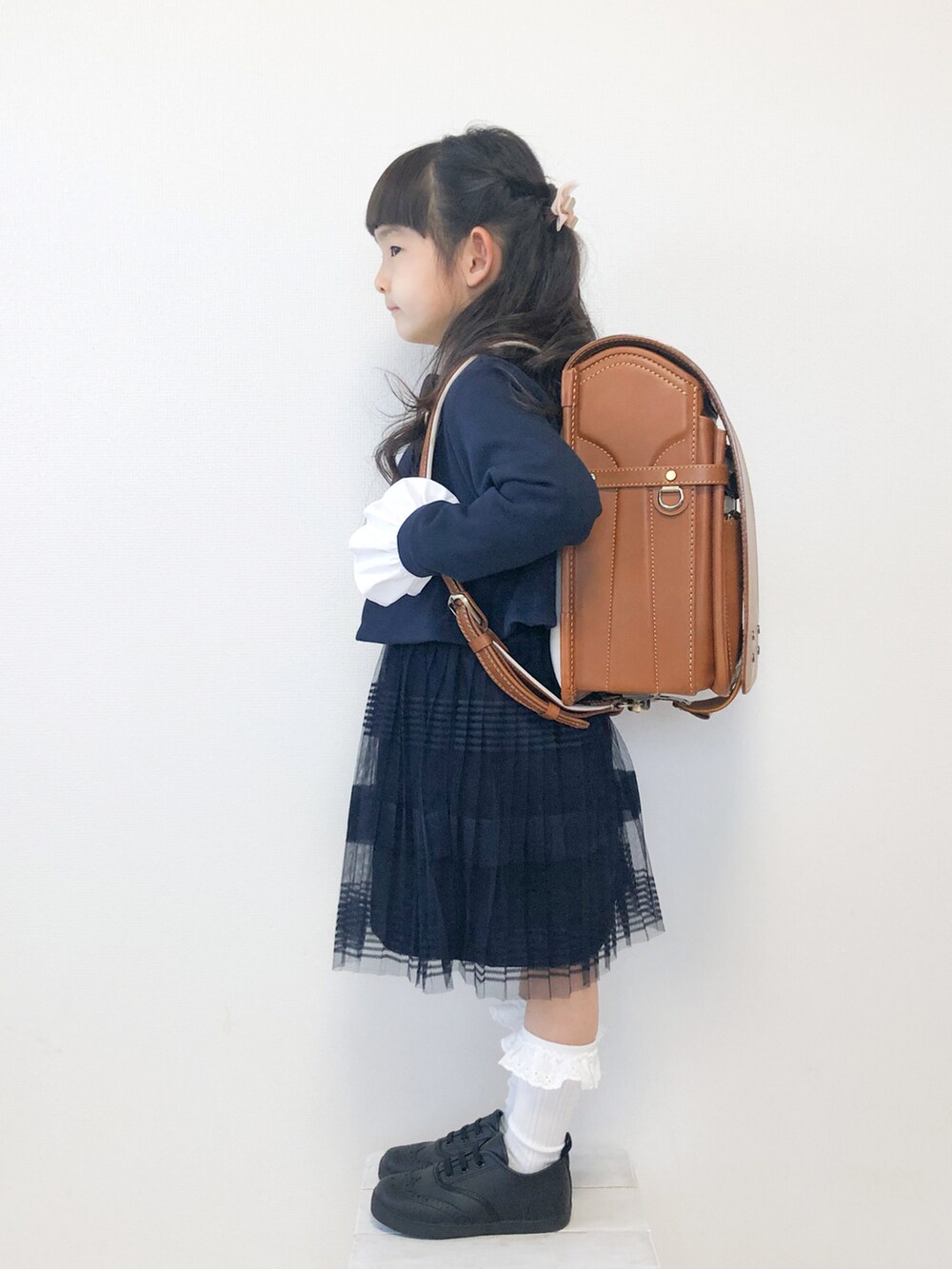 ブラック系のドレスシューズ、ホワイト系のシャツ/ブラウス、ブルー系のスカートを着用したキッズの春コーディネートの2枚目の写真