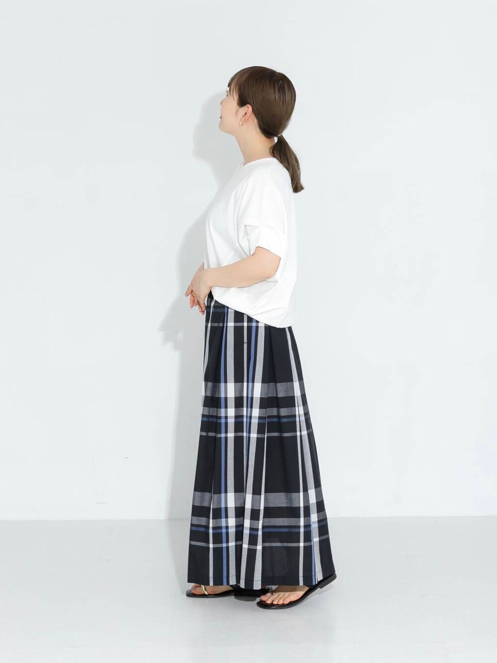 ブラック系のスカート、ホワイト系のTシャツ/カットソーを着用したレディースの春コーディネートの2枚目の写真