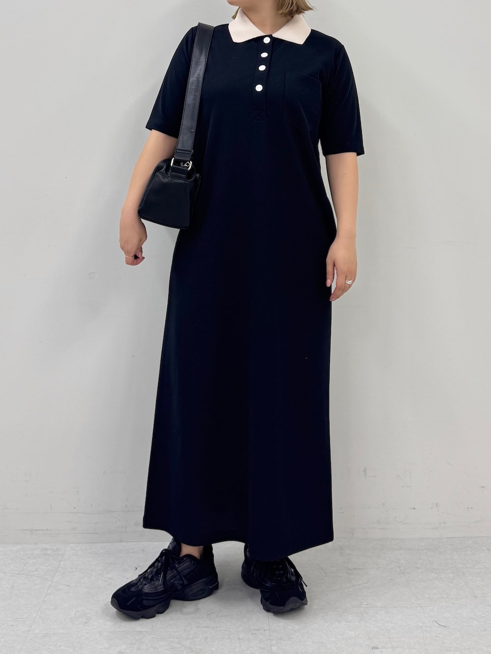 ブラック系のワンピース、ブラック系のスニーカー、ブラック系のショルダーバッグを着用したレディースの春コーディネートの4枚目の写真