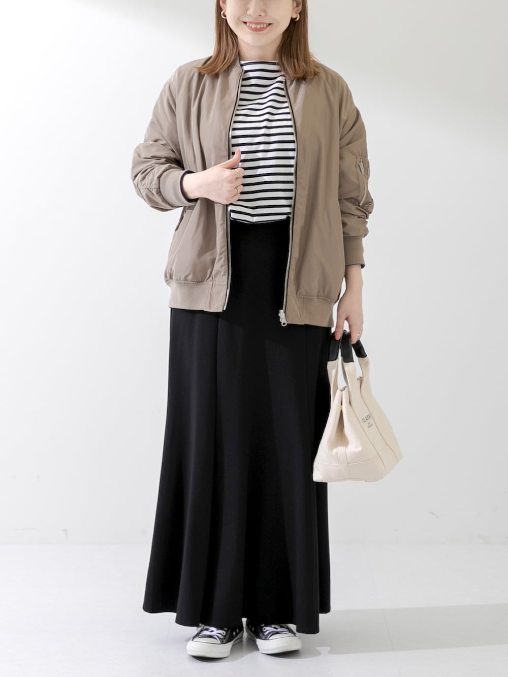 ホワイト系のトートバッグ、ブラック系のTシャツ/カットソー、ブラック系のスカートを着用したレディースの春コーディネートの2枚目の写真