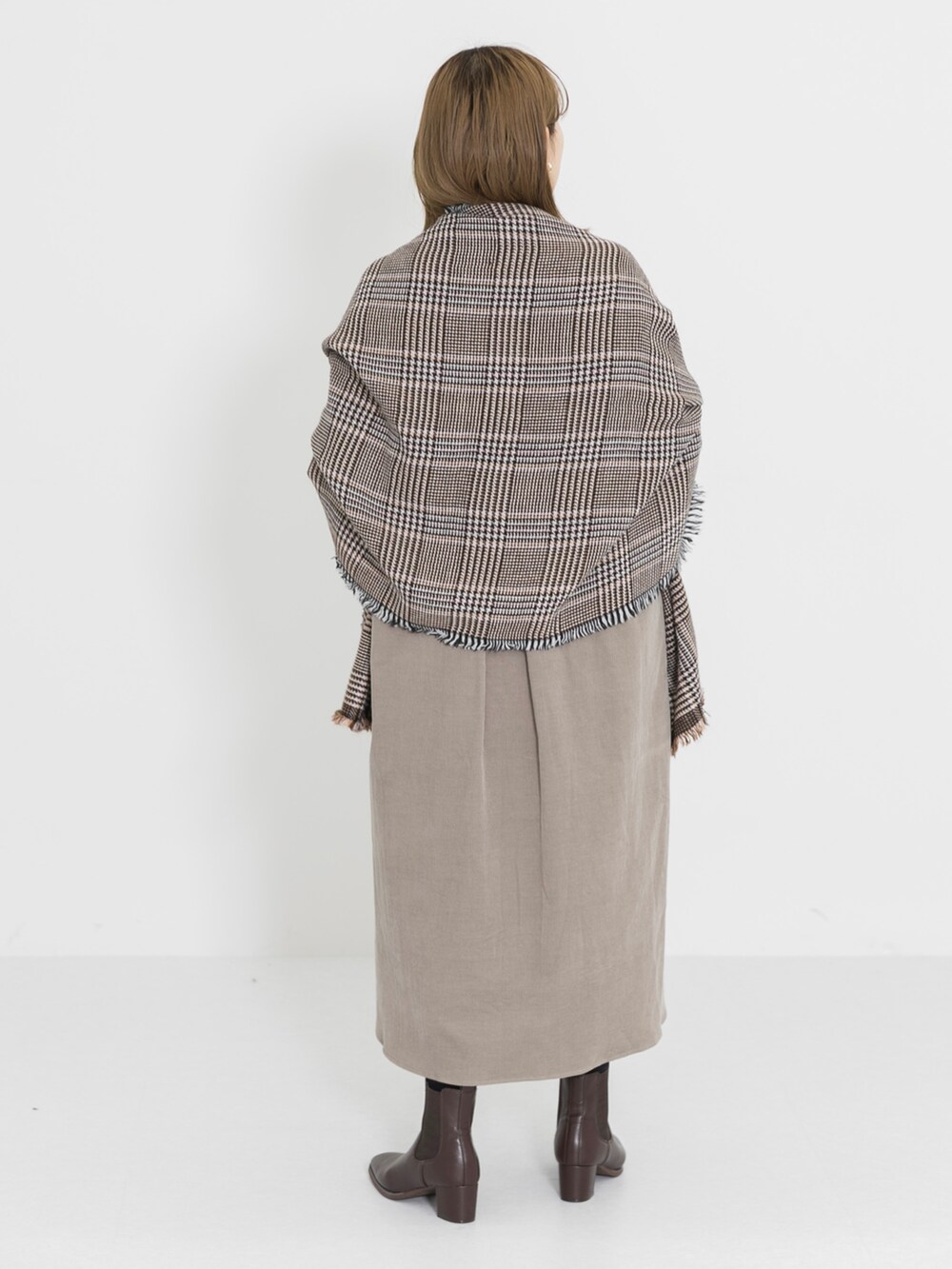 ブラウン系のブーツ、ベージュ系のワンピース、ブラウン系のハンドバッグを着用したレディースの冬コーディネートの4枚目の写真