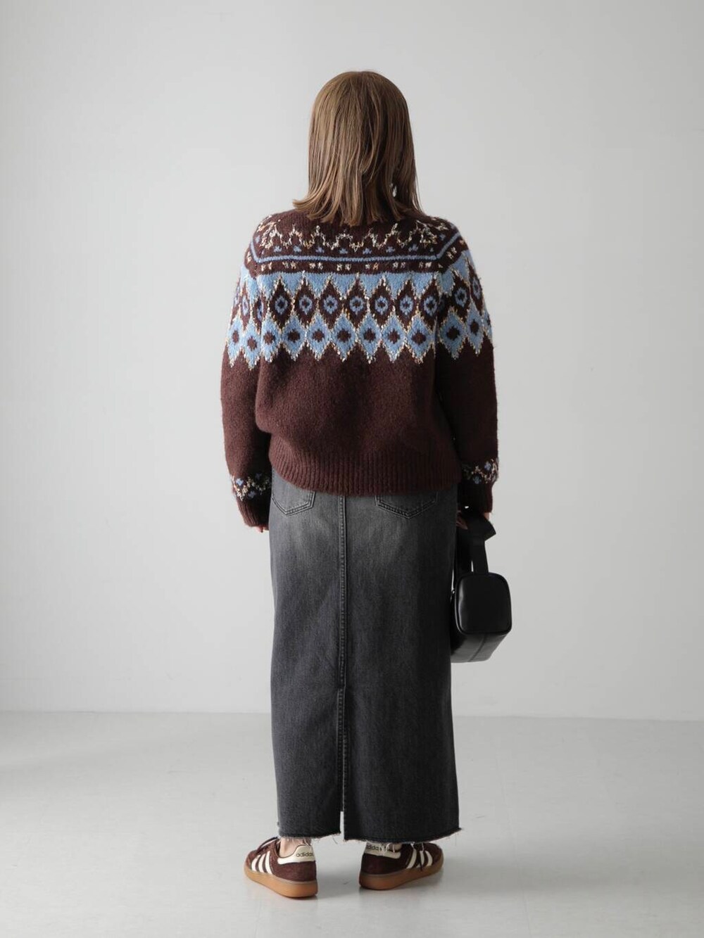 ブラック系のショルダーバッグ、ブラウン系のカーディガン/ボレロ、ブラック系のデニムスカートを着用したレディースの秋コーディネートの3枚目の写真