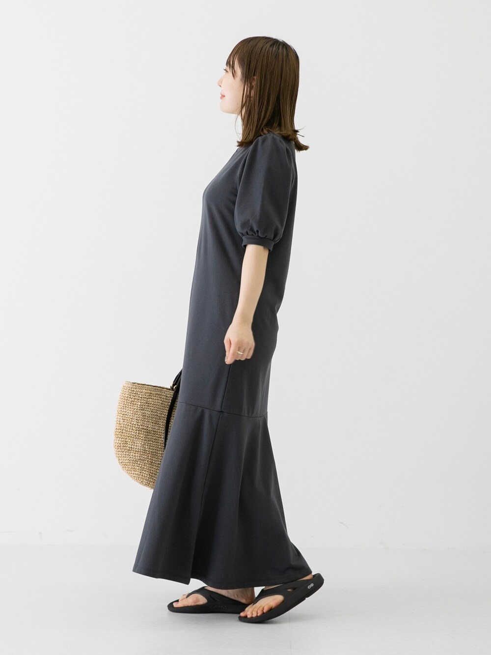 ベージュ系のショルダーバッグ、グレー系のワンピース、ブラック系のサンダルを着用したレディースの夏コーディネートの3枚目の写真