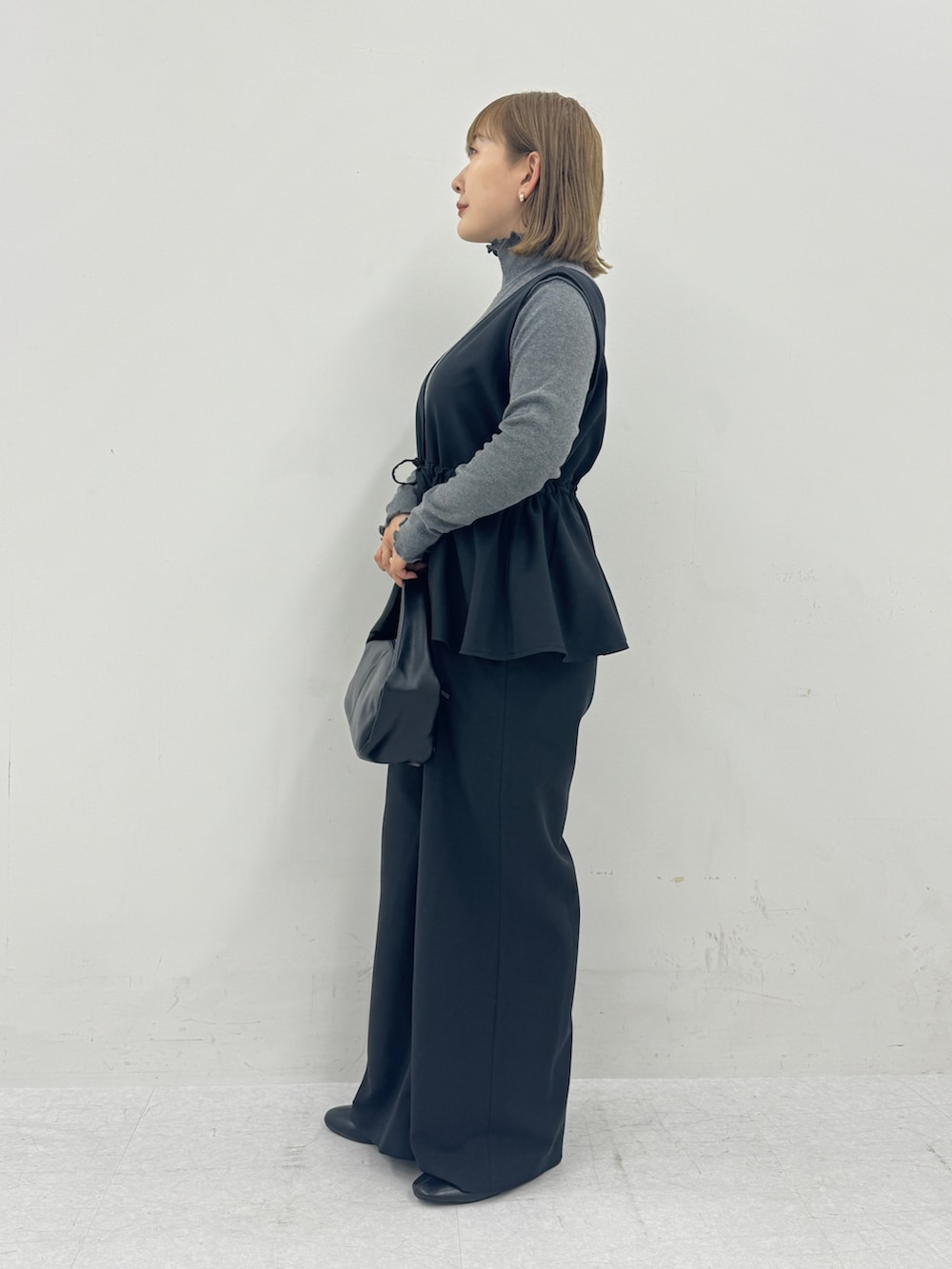 ブラック系のつなぎ/オールインワン、グレー系のTシャツ/カットソー、ゴールド系のイヤリングを着用したレディースの秋コーディネートの2枚目の写真