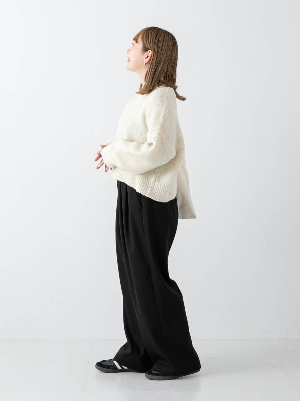 ブラック系のその他パンツ、ホワイト系のニット/セーター、ホワイト系のトートバッグを着用したレディースの冬コーディネートの2枚目の写真