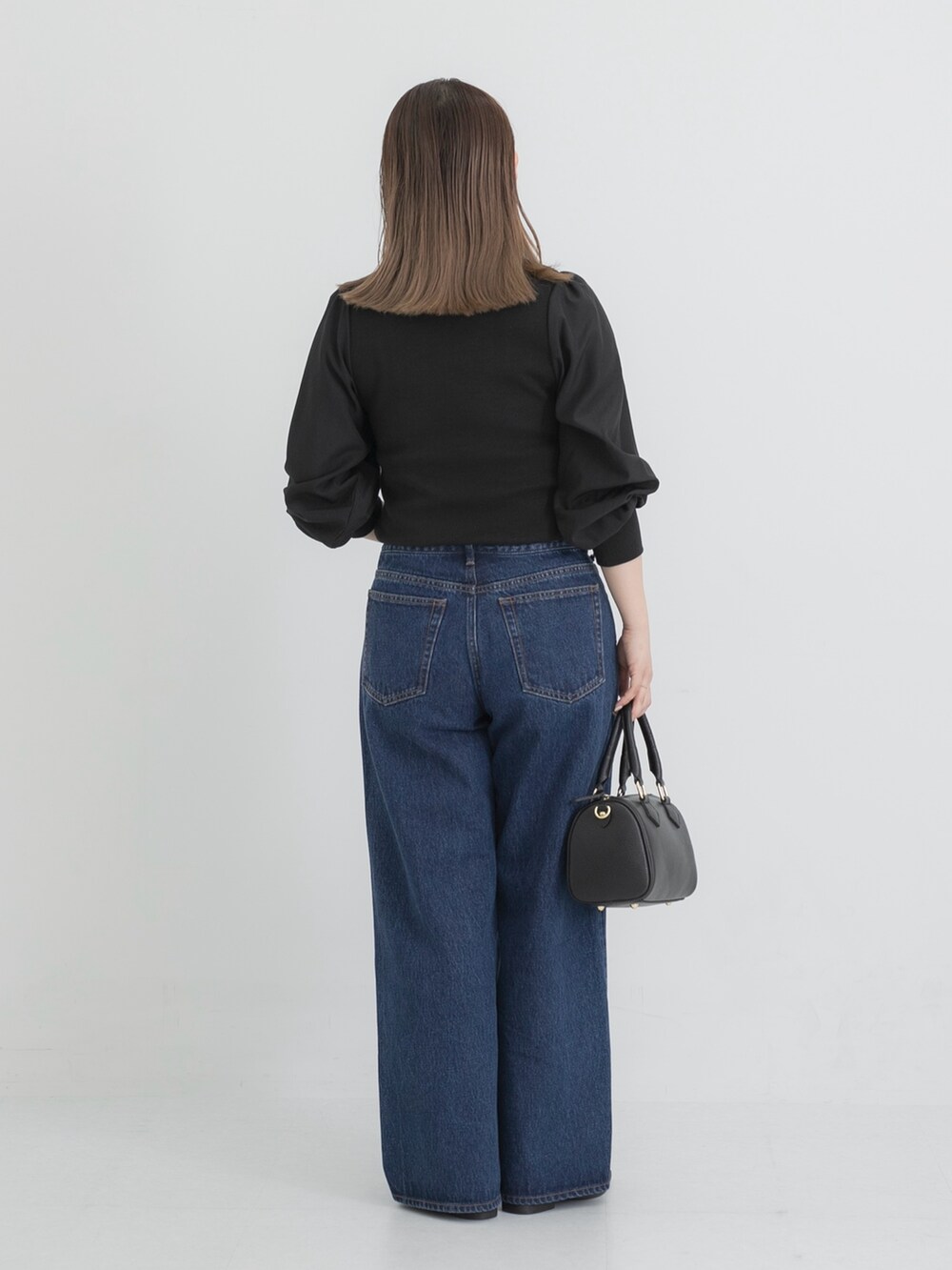 ブルー系のデニムパンツ、ブラック系のボストンバッグ、ブラック系のその他シューズを着用したレディースの秋コーディネートの3枚目の写真