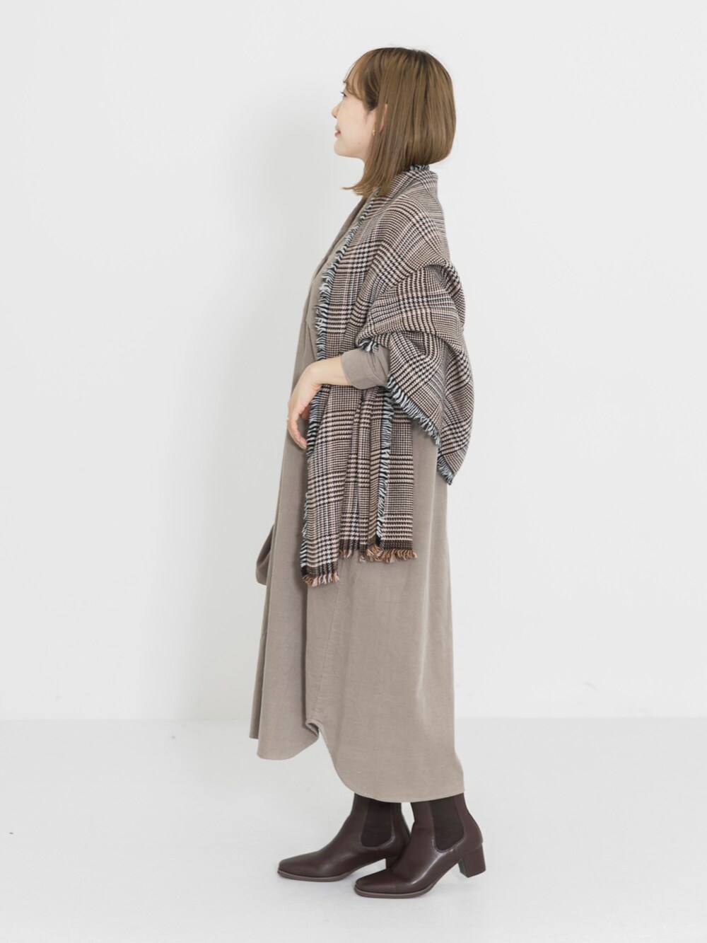 ブラウン系のブーツ、ベージュ系のワンピース、ブラウン系のハンドバッグを着用したレディースの冬コーディネートの3枚目の写真