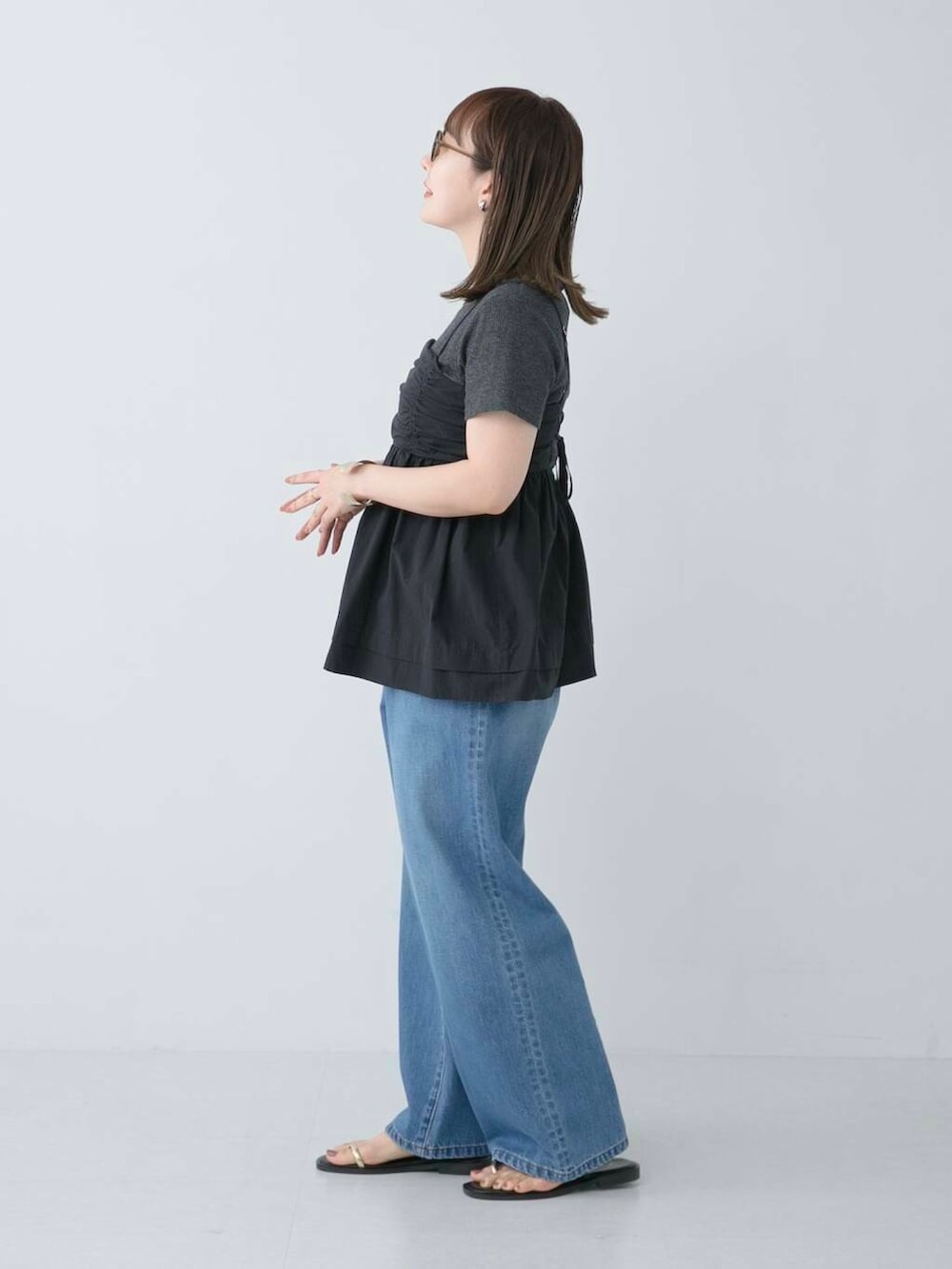 グレー系のTシャツ/カットソー、ブラック系のサンダル、ブルー系のデニムパンツを着用したレディースの夏コーディネートの2枚目の写真