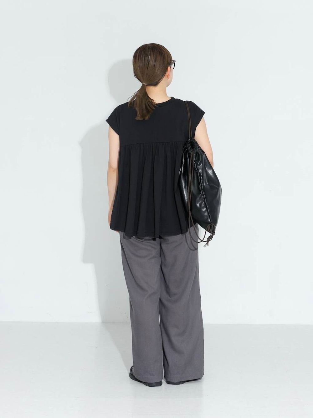 グレー系のその他パンツ、ブラック系のTシャツ/カットソー、ブラック系のバックパック/リュックを着用したレディースの春コーディネートの3枚目の写真