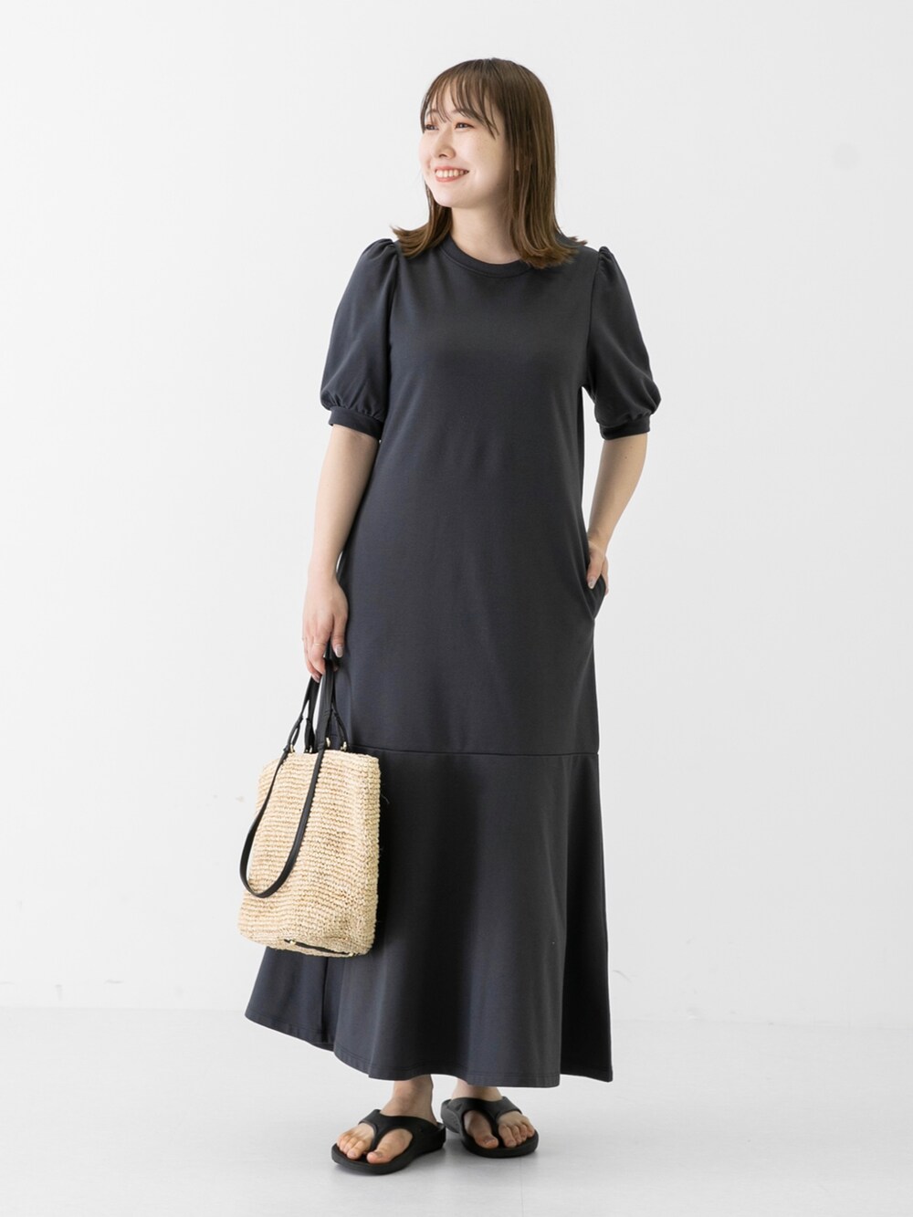 ベージュ系のショルダーバッグ、グレー系のワンピース、ブラック系のサンダルを着用したレディースの夏コーディネートの2枚目の写真