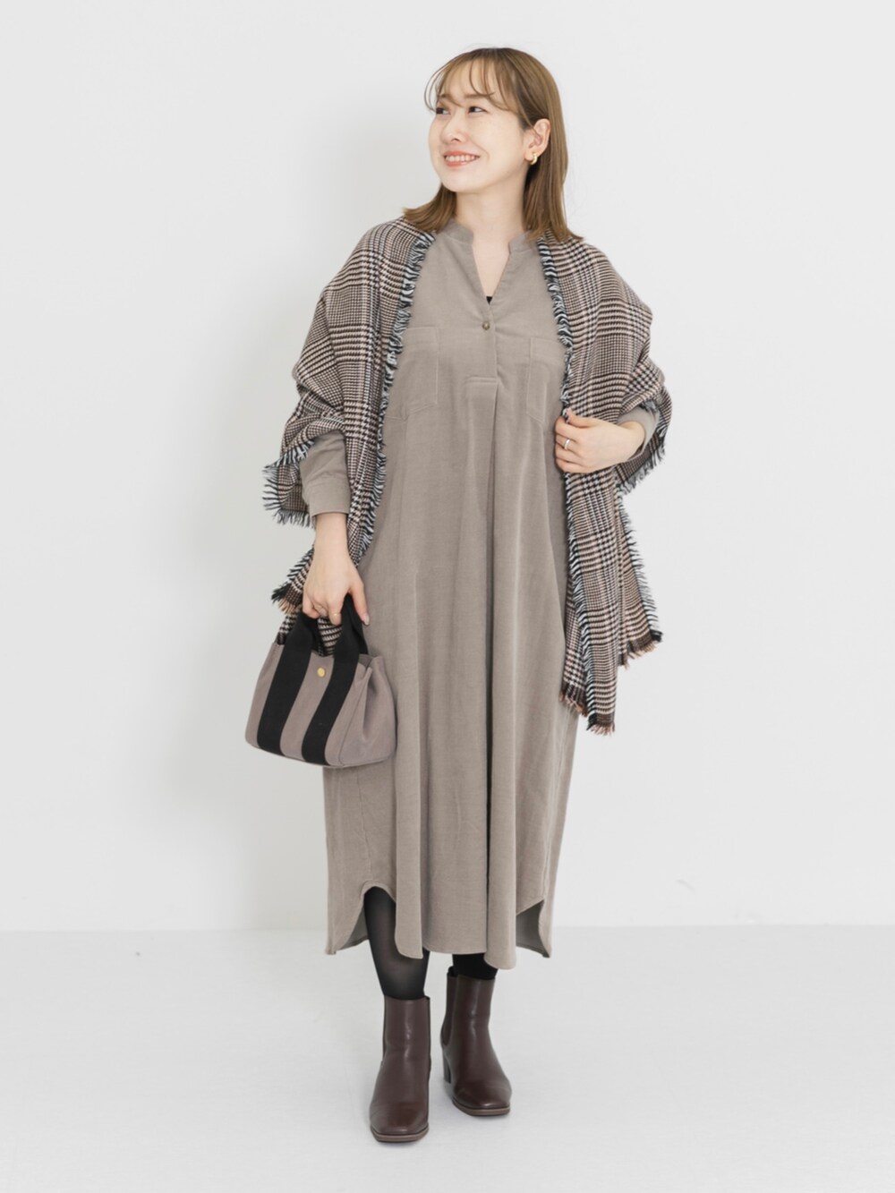 ブラウン系のブーツ、ベージュ系のワンピース、ブラウン系のハンドバッグを着用したレディースの冬コーディネートの2枚目の写真