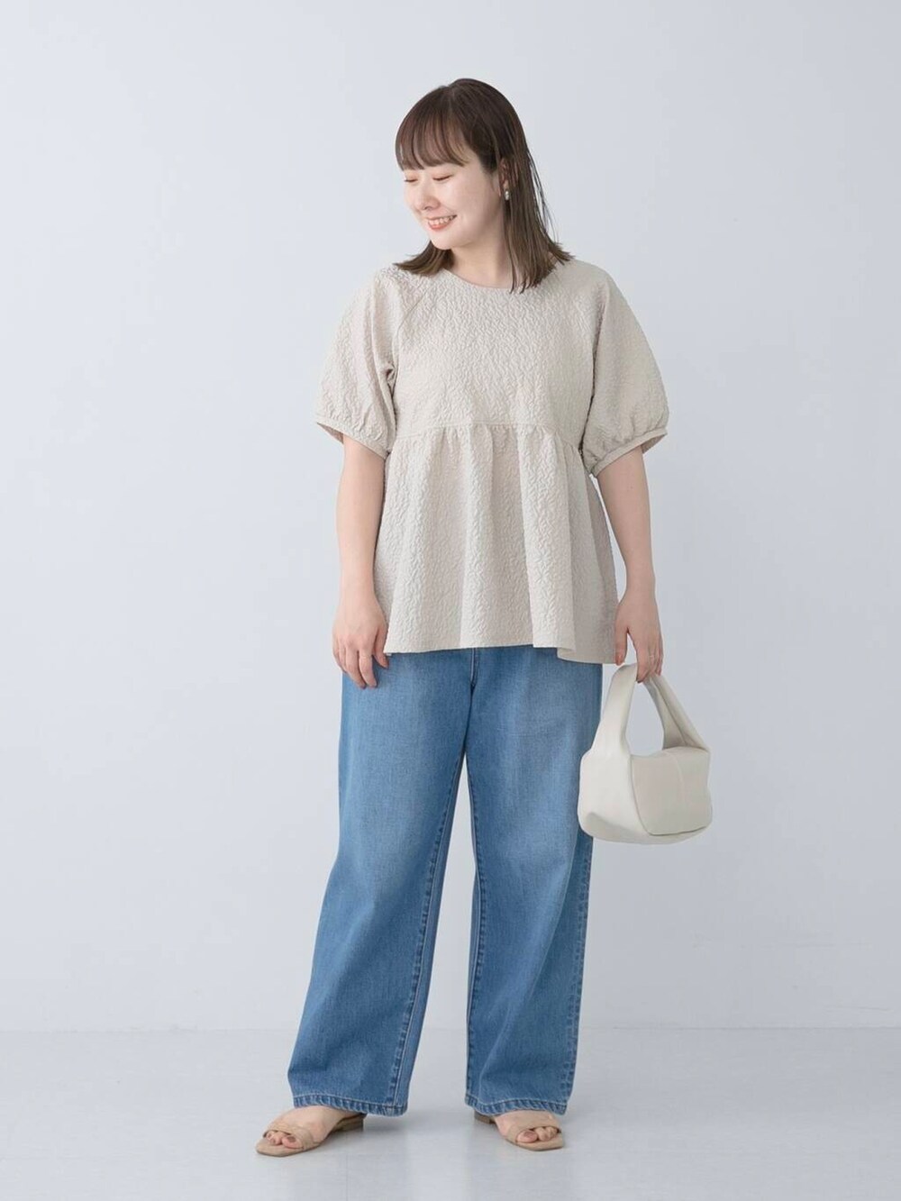 ベージュ系のシャツ/ブラウス、ブルー系のデニムパンツを着用したレディースの夏コーディネートの2枚目の写真