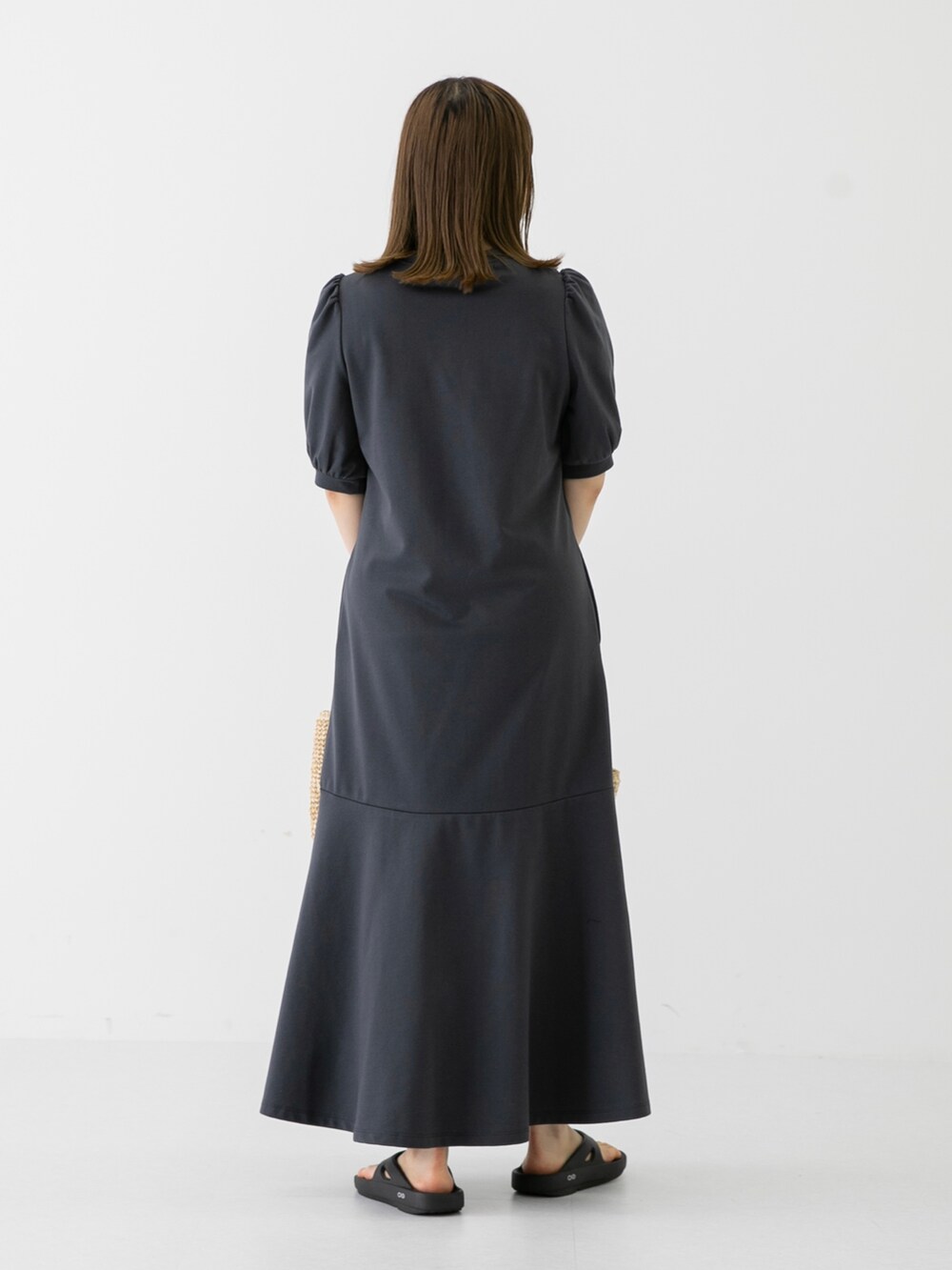 ベージュ系のショルダーバッグ、グレー系のワンピース、ブラック系のサンダルを着用したレディースの夏コーディネートの4枚目の写真