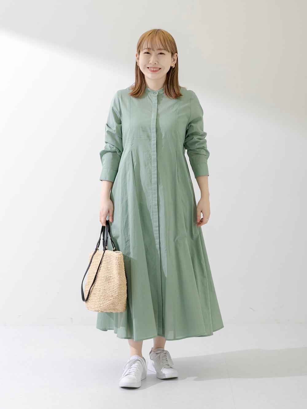 グリーン系のワンピース、ゴールド系のイヤリングを着用したレディースの春コーディネートの2枚目の写真