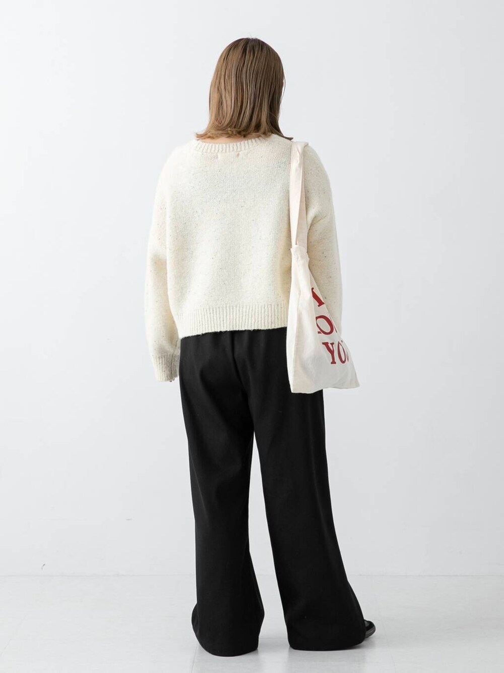 ブラック系のその他パンツ、ホワイト系のニット/セーター、ホワイト系のトートバッグを着用したレディースの冬コーディネートの3枚目の写真