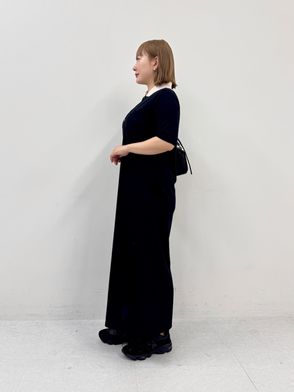 ブラック系のワンピース、ブラック系のスニーカー、ブラック系のショルダーバッグを着用したレディースの春コーディネートの2枚目の写真