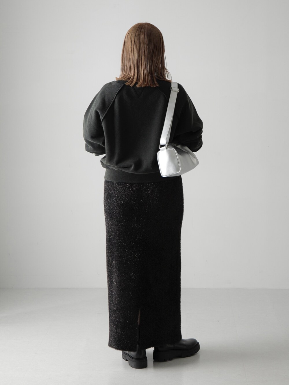 ブラック系のスカート、ブラック系のスウェット、シルバー系のショルダーバッグを着用したレディースの秋コーディネートの3枚目の写真