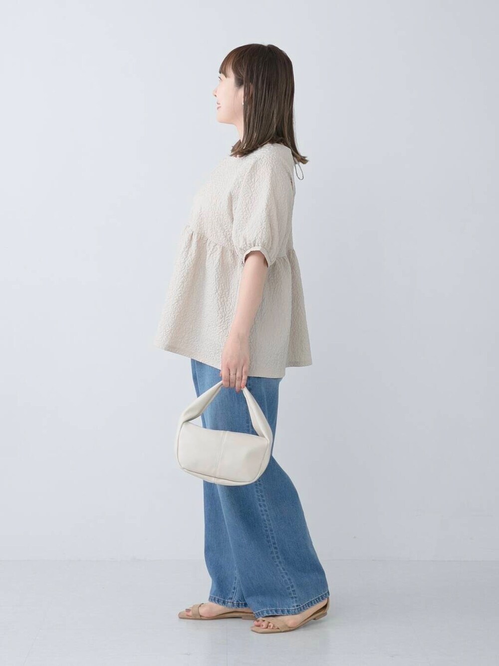 ベージュ系のシャツ/ブラウス、ブルー系のデニムパンツを着用したレディースの夏コーディネートの3枚目の写真