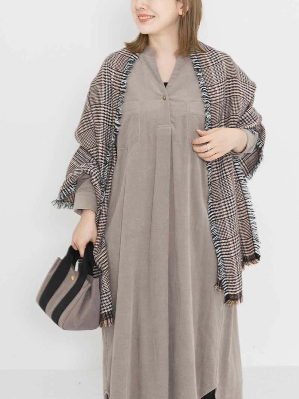 ブラウン系のブーツ、ベージュ系のワンピース、ブラウン系のハンドバッグを着用したレディースの冬コーディネートの5枚目の写真