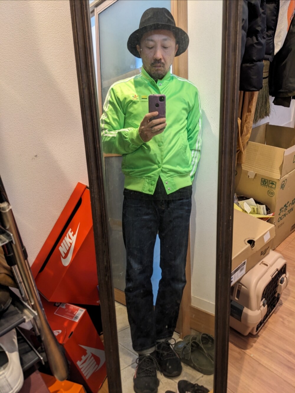 グリーン系のブルゾン、ブラック系のTシャツ/カットソー、ブルー系のデニムパンツを着用したメンズの秋コーディネートの2枚目の写真