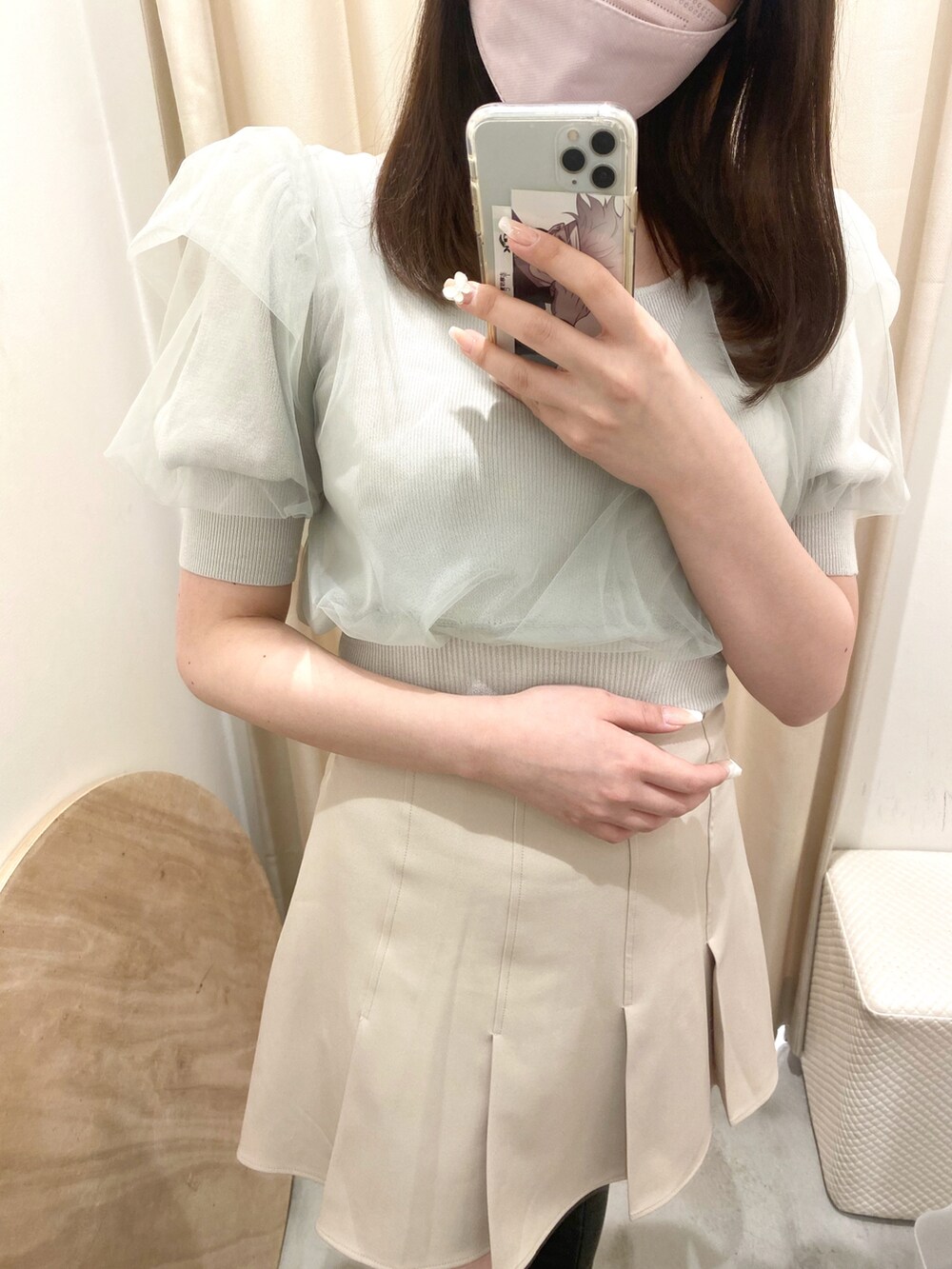 グリーン系のトップス、ベージュ系のスカート、ブラック系のブーツを着用したレディースの春コーディネートの2枚目の写真