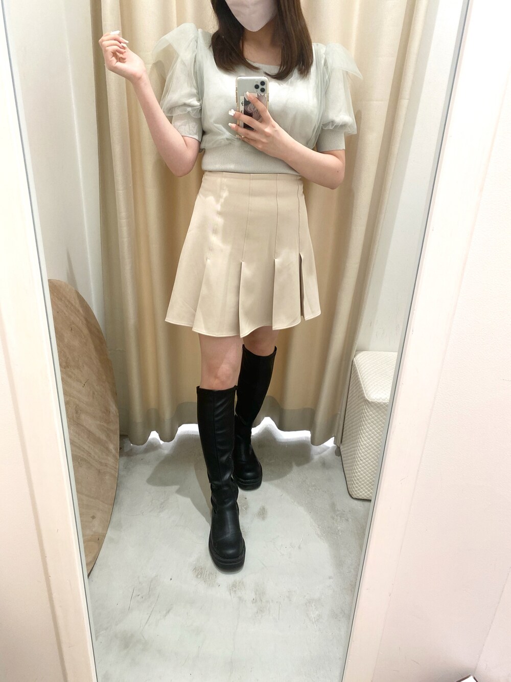 グリーン系のトップス、ベージュ系のスカート、ブラック系のブーツを着用したレディースの春コーディネートの3枚目の写真