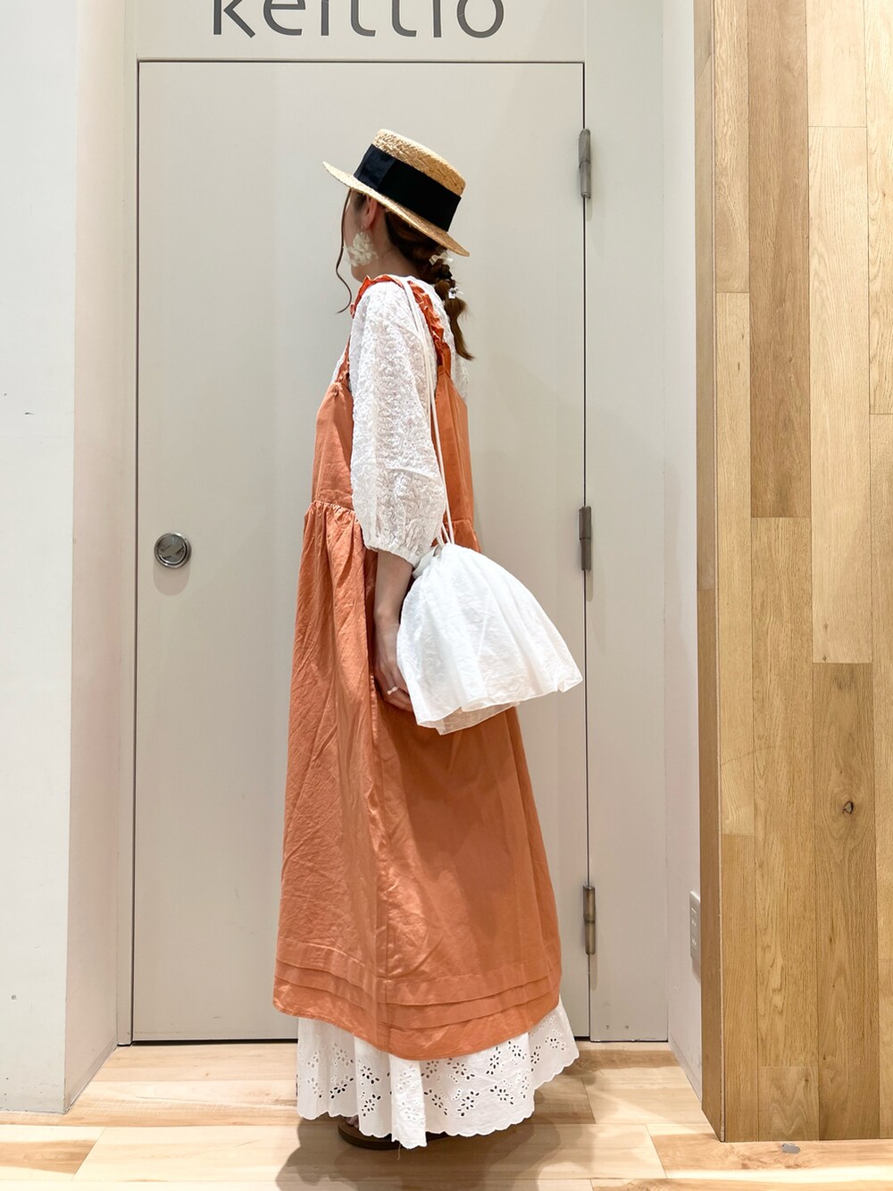 オレンジ系のワンピース/ドレス、ホワイト系のTシャツ/カットソー、ホワイト系のハンドバッグを着用したレディースの夏コーディネートの2枚目の写真