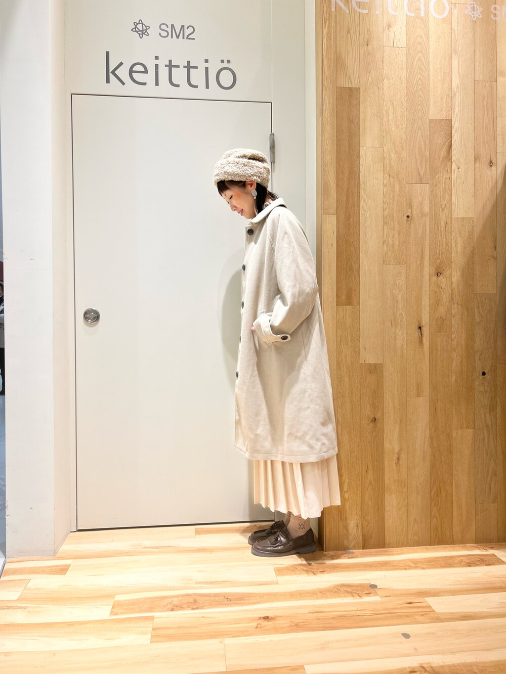 ベージュ系のシャツ/ブラウス、ベージュ系のステンカラーコート、ホワイト系のスカートを着用したレディースの冬コーディネートの2枚目の写真