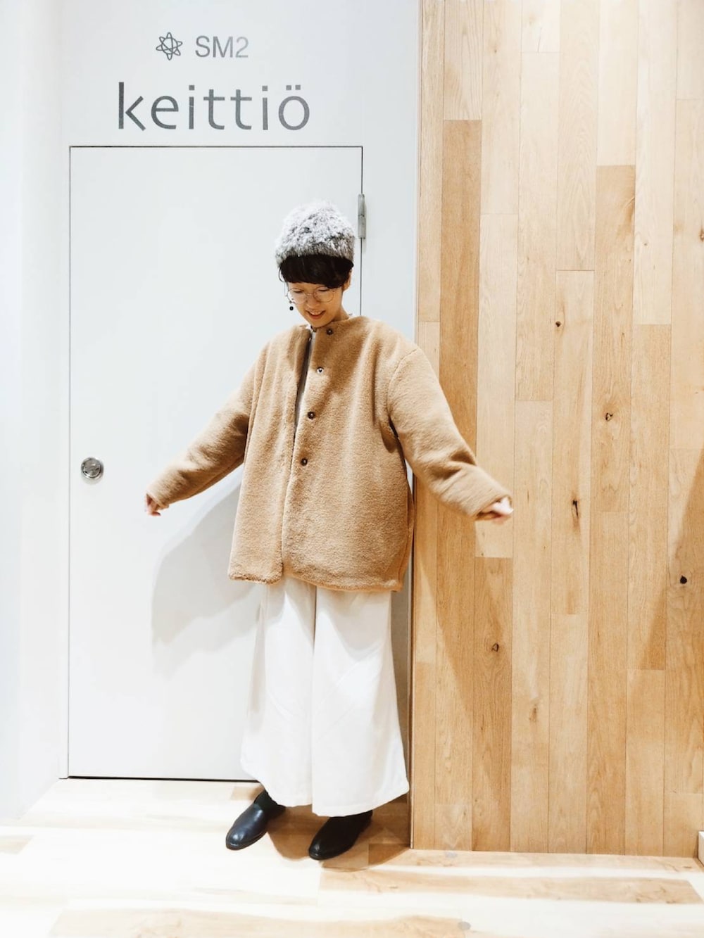 ベージュ系のノーカラーコート、ホワイト系のその他パンツ、ブラック系のその他シューズを着用したレディースの冬コーディネートの2枚目の写真