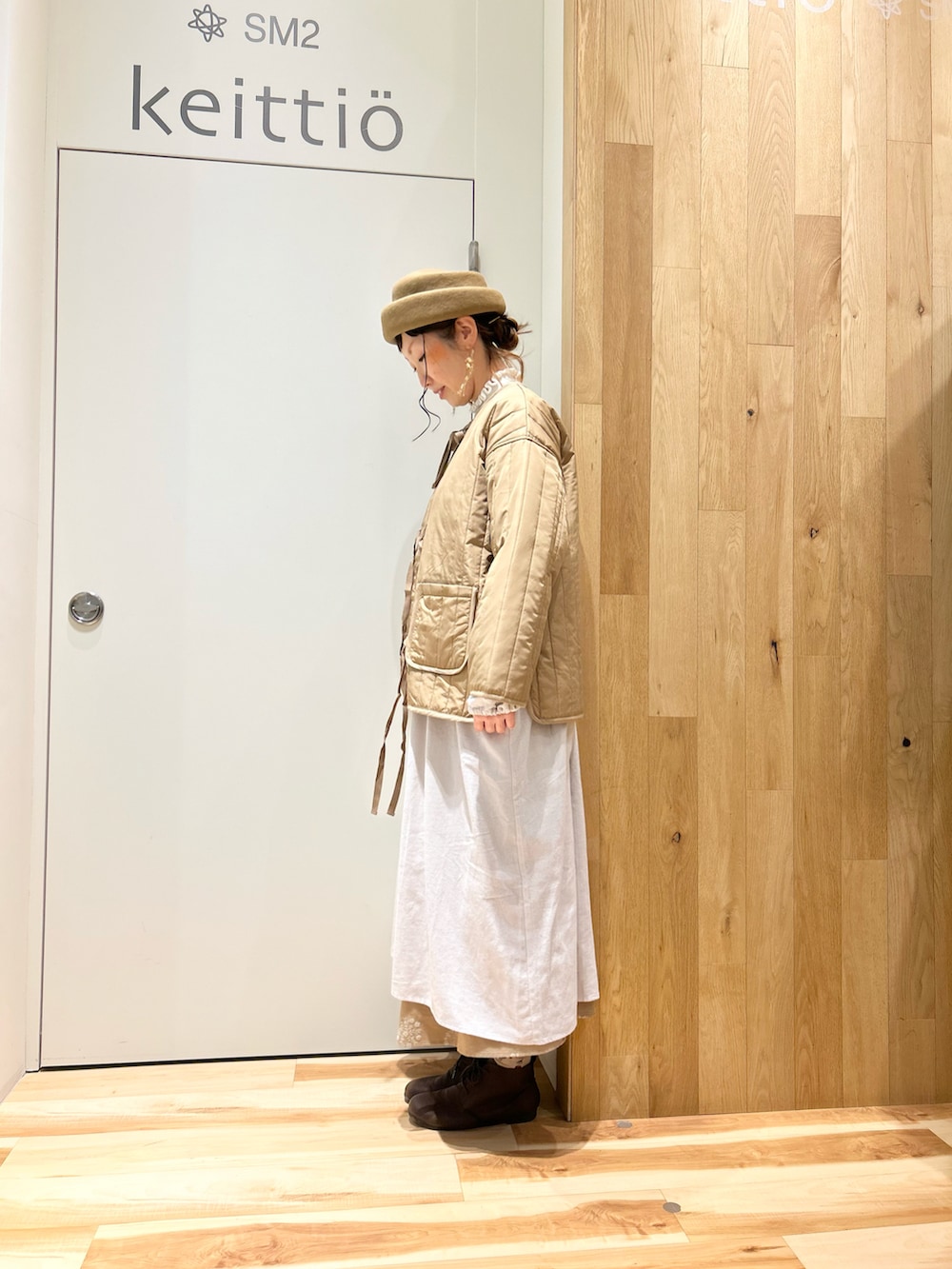 ベージュ系のノーカラージャケット、グレー系のワンピース、ホワイト系のベストを着用したレディースの冬コーディネートの2枚目の写真