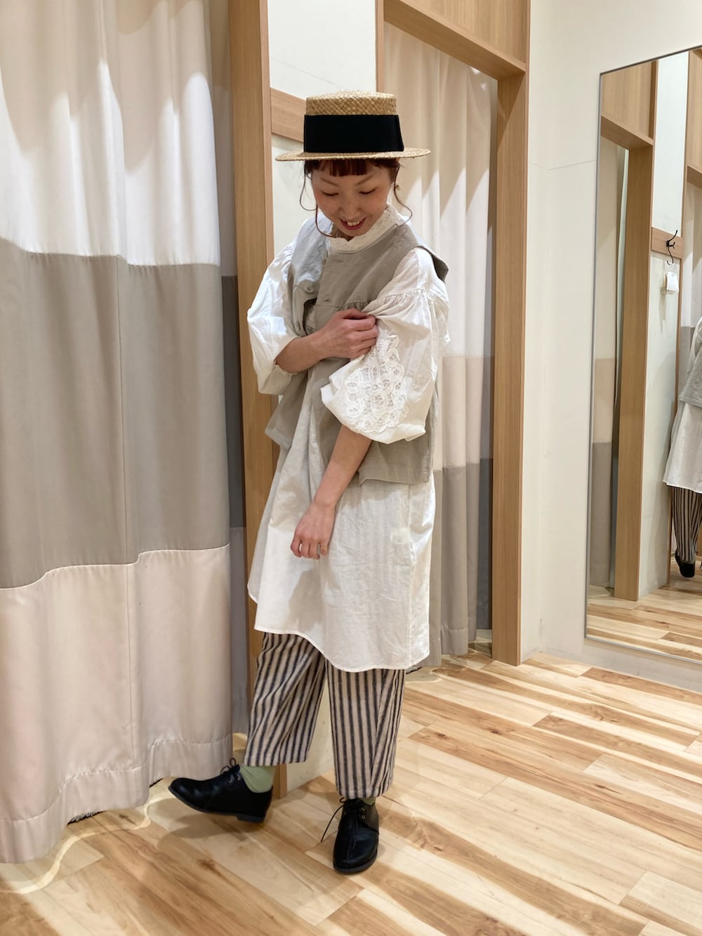 ホワイト系のチュニック、ベージュ系のベスト、グレー系のその他パンツを着用したレディースの春コーディネートの2枚目の写真