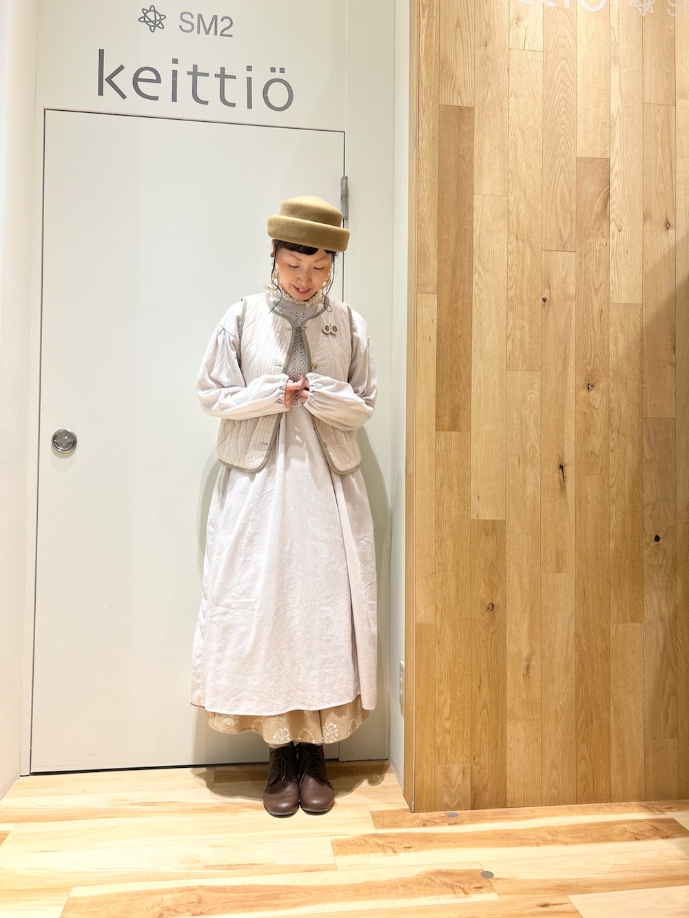 ベージュ系のノーカラージャケット、グレー系のワンピース、ホワイト系のベストを着用したレディースの冬コーディネートの4枚目の写真