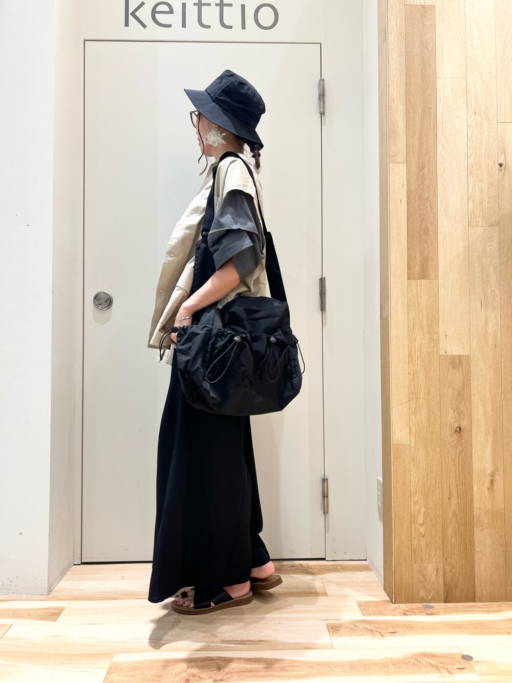 ブラック系のTシャツ/カットソー、ベージュ系のベスト、ブラック系のバッグを着用したレディースの夏コーディネートの2枚目の写真