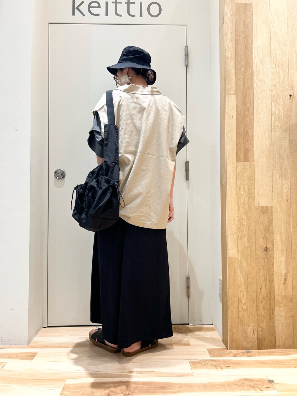 ブラック系のTシャツ/カットソー、ベージュ系のベスト、ブラック系のバッグを着用したレディースの夏コーディネートの3枚目の写真