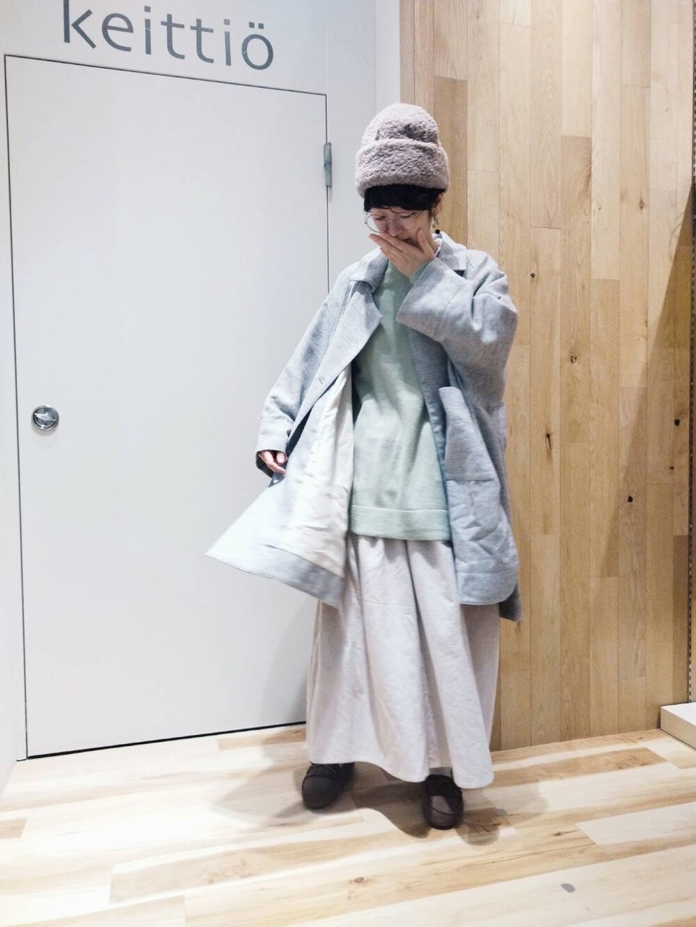 グリーン系のニット/セーター、グレー系のポンチョ、ホワイト系のその他パンツを着用したレディースの冬コーディネートの2枚目の写真