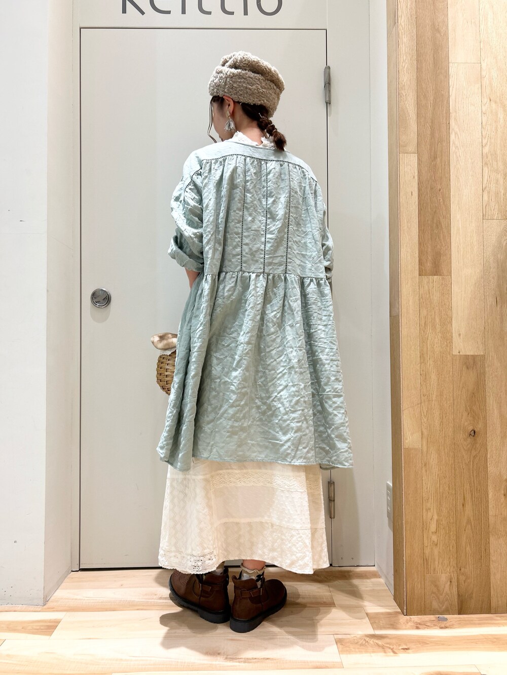 グリーン系のチュニック、ホワイト系のスカート、ブラウン系のブーツを着用したレディースの冬コーディネートの3枚目の写真