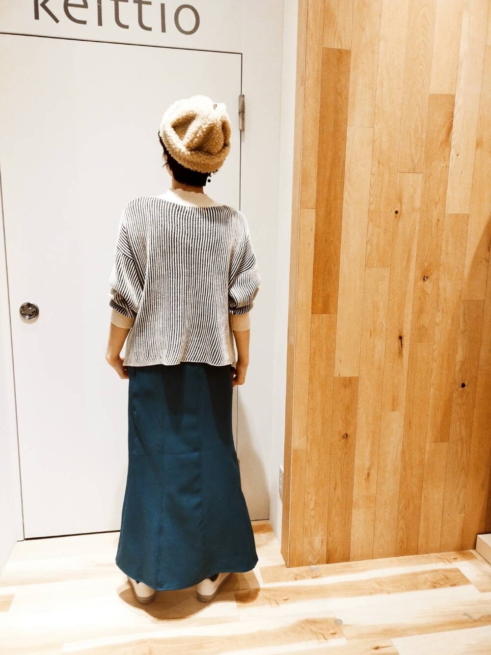 グリーン系のスカート、ブラック系のニット/セーターを着用したレディースの冬コーディネートの2枚目の写真