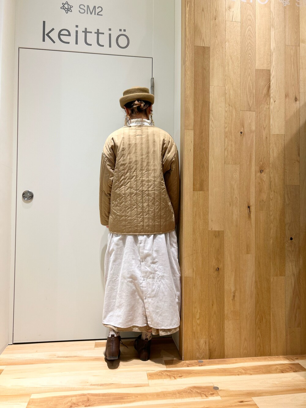 ベージュ系のノーカラージャケット、グレー系のワンピース、ホワイト系のベストを着用したレディースの冬コーディネートの3枚目の写真