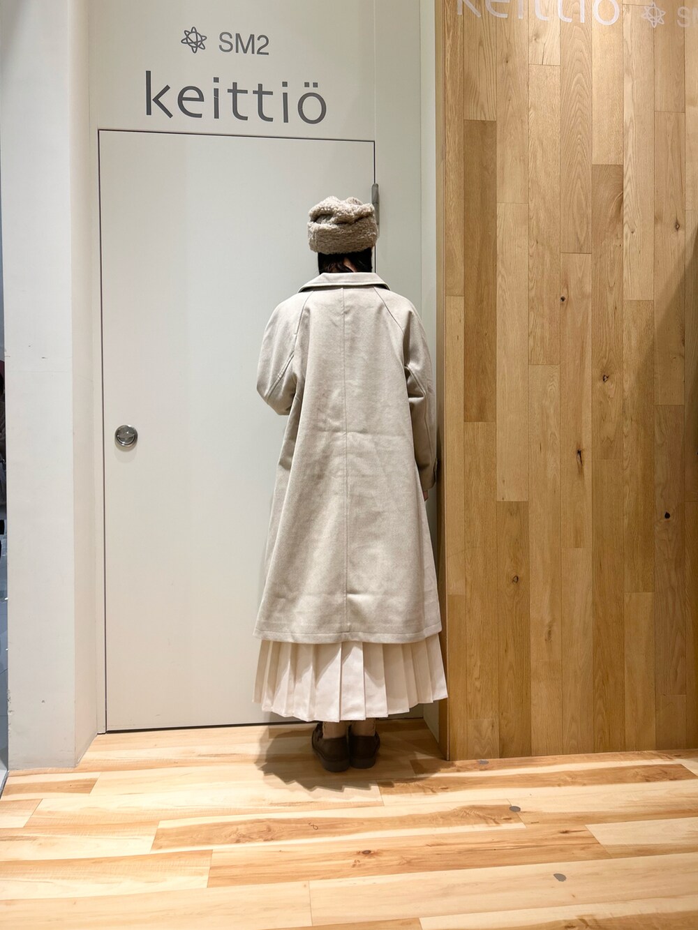 ベージュ系のシャツ/ブラウス、ベージュ系のステンカラーコート、ホワイト系のスカートを着用したレディースの冬コーディネートの3枚目の写真