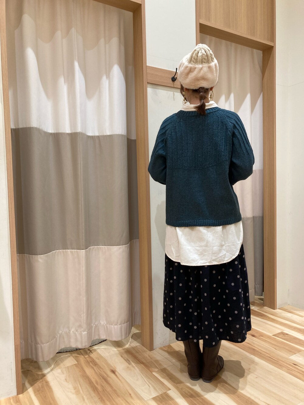 グリーン系のニット/セーター、ホワイト系のシャツ/ブラウス、ブラウン系のブーツを着用したレディースの冬コーディネートの2枚目の写真