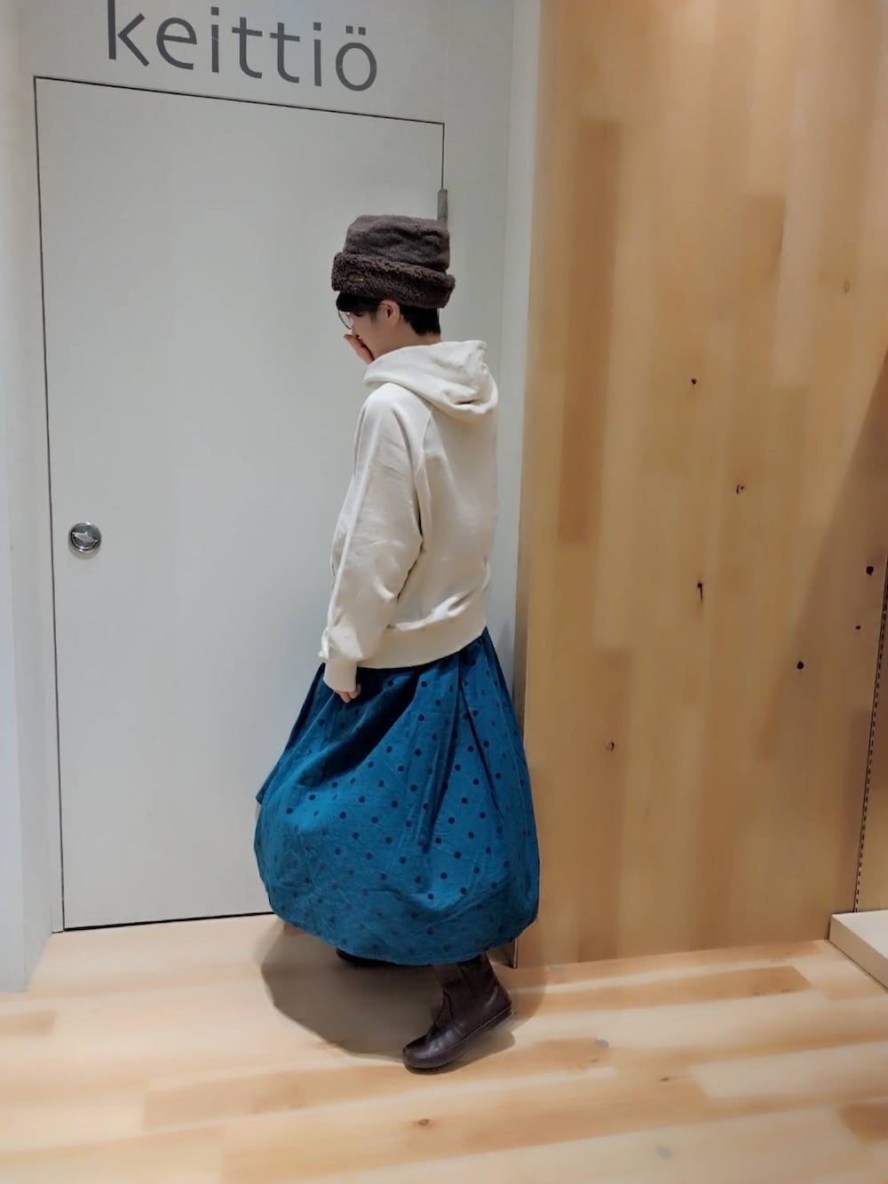 グリーン系のスカート、ブラウン系のブーツ、ホワイト系のパーカーを着用したレディースの冬コーディネートの2枚目の写真