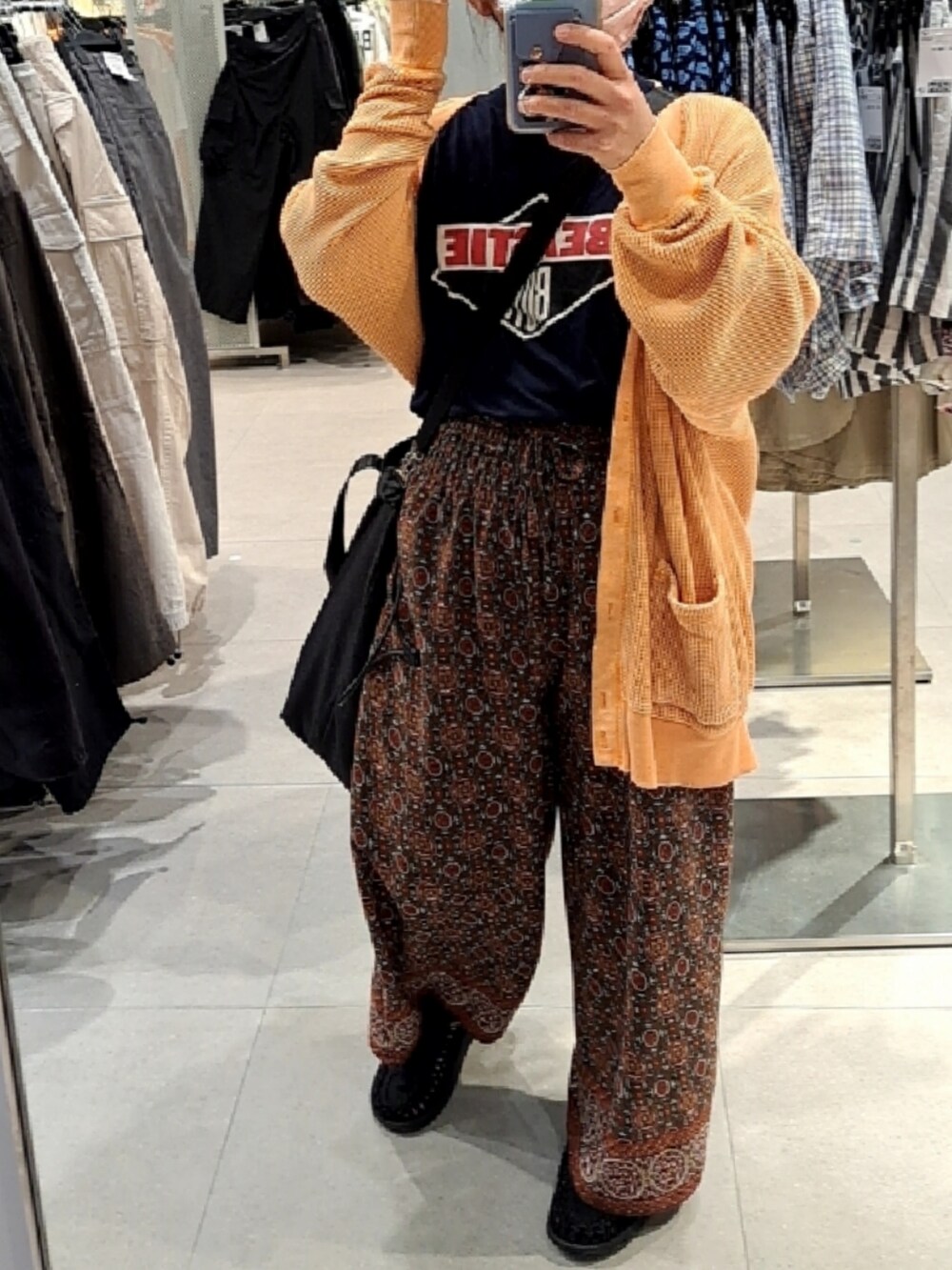 ブラック系のTシャツ/カットソー、オレンジ系のカーディガン/ボレロ、ブラウン系のその他パンツを着用したレディースの春コーディネートの2枚目の写真