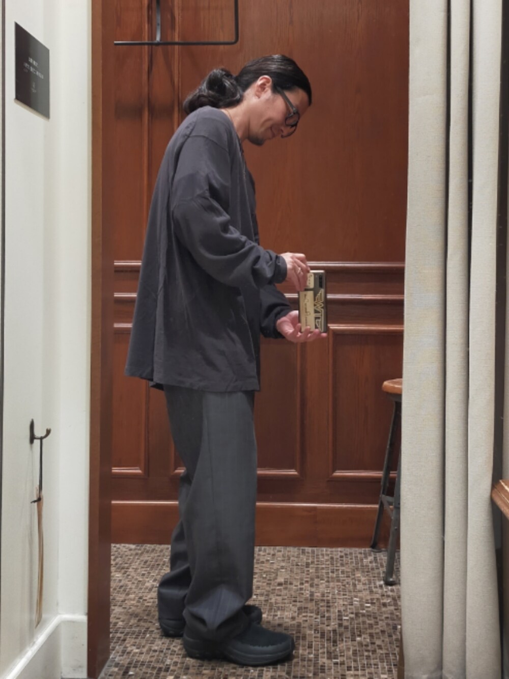 グレー系のTシャツ/カットソー、グレー系のスラックス、ブラック系のスニーカーを着用したメンズの秋コーディネートの3枚目の写真