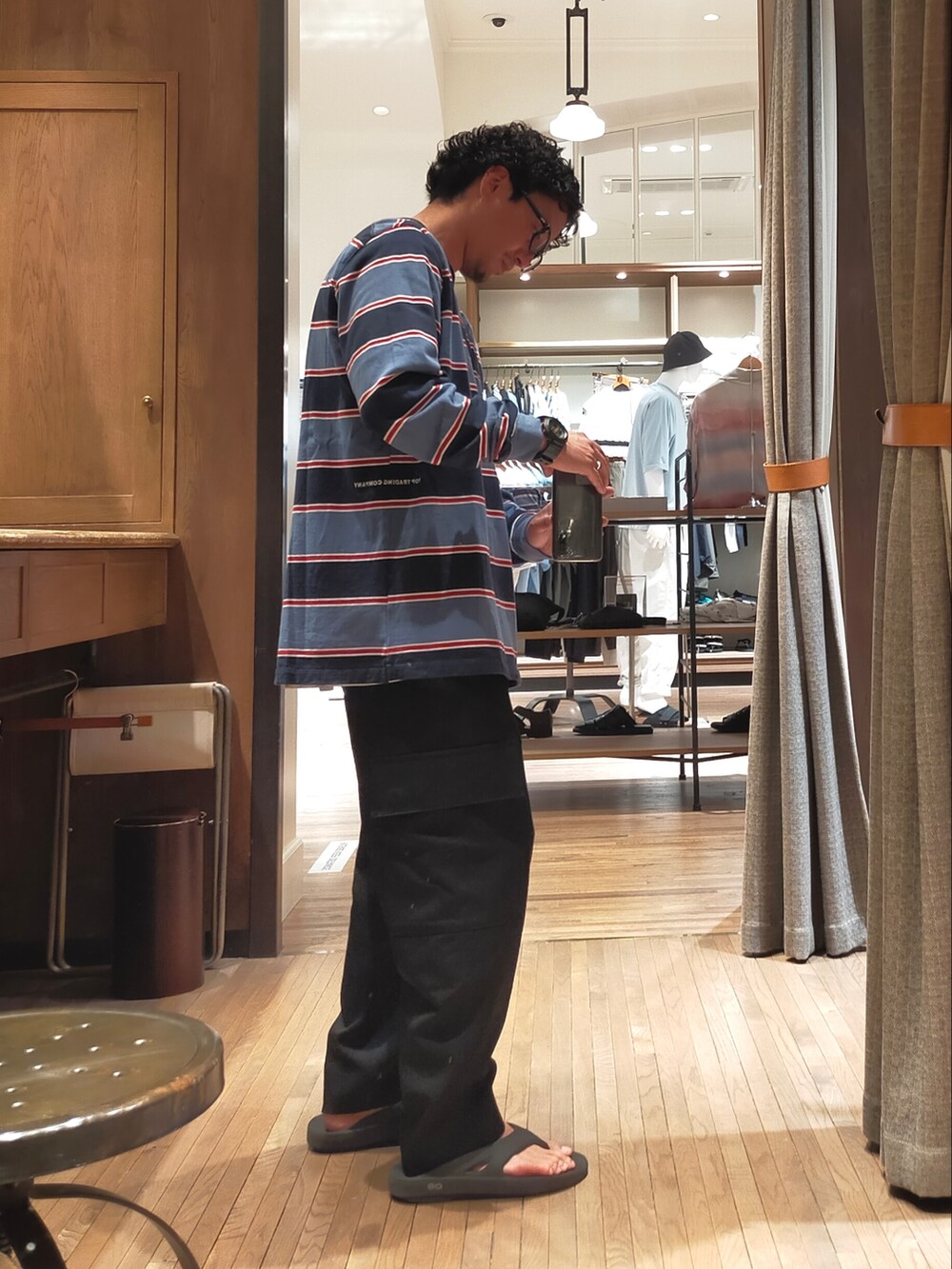 ブルー系のTシャツ/カットソー、ブラック系のスラックス、ブラック系のサンダルを着用したメンズの夏コーディネートの2枚目の写真